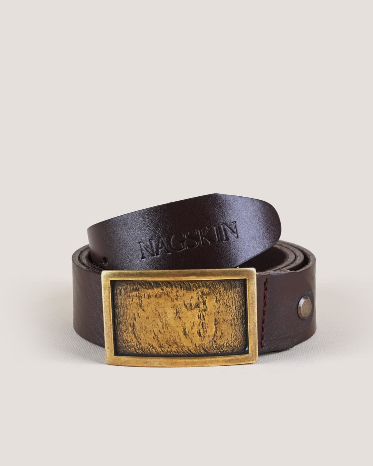 A dark brown belt with a rectangular antique-brass plate buckle, the plate's face textured in mottled gold