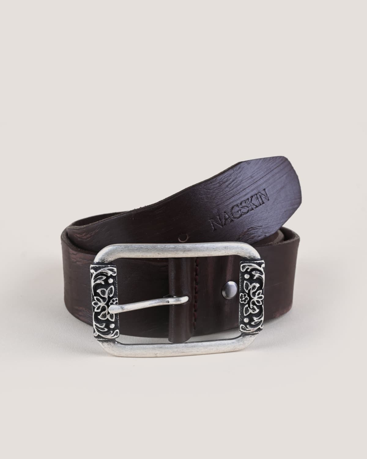 A dark brown belt with a heavier grain, its silver buckle set with two blackened panels of floral filigree either side of the pin