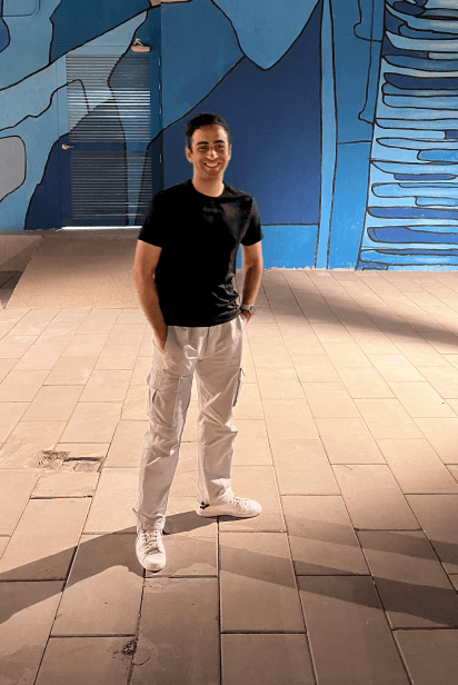 Omar Sadek standing in front of a blue mural at night